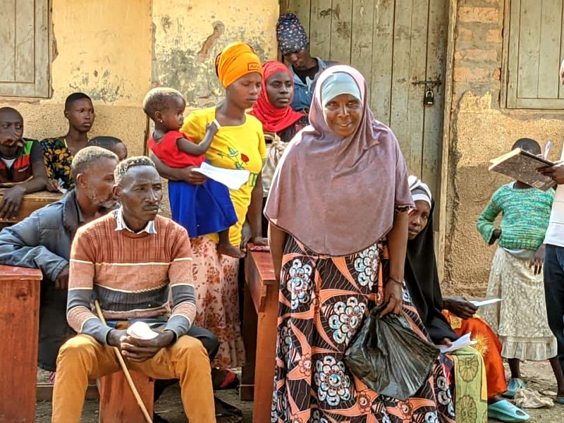 People wait on benches outside a school for an outreach day to start