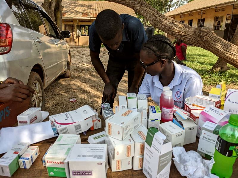 Boxes of medicines and bottles of syrup laid out on a desk at an outreach day pharmacy