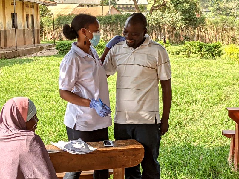 Two MANCO team members laugh together on the grass at an outreach site